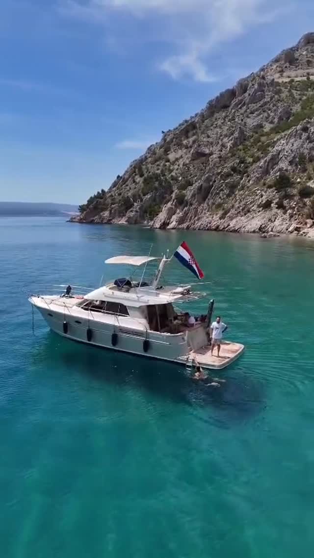 Motor yacht Providenca at anchor beneath the cliffs, flying the Croatian flag