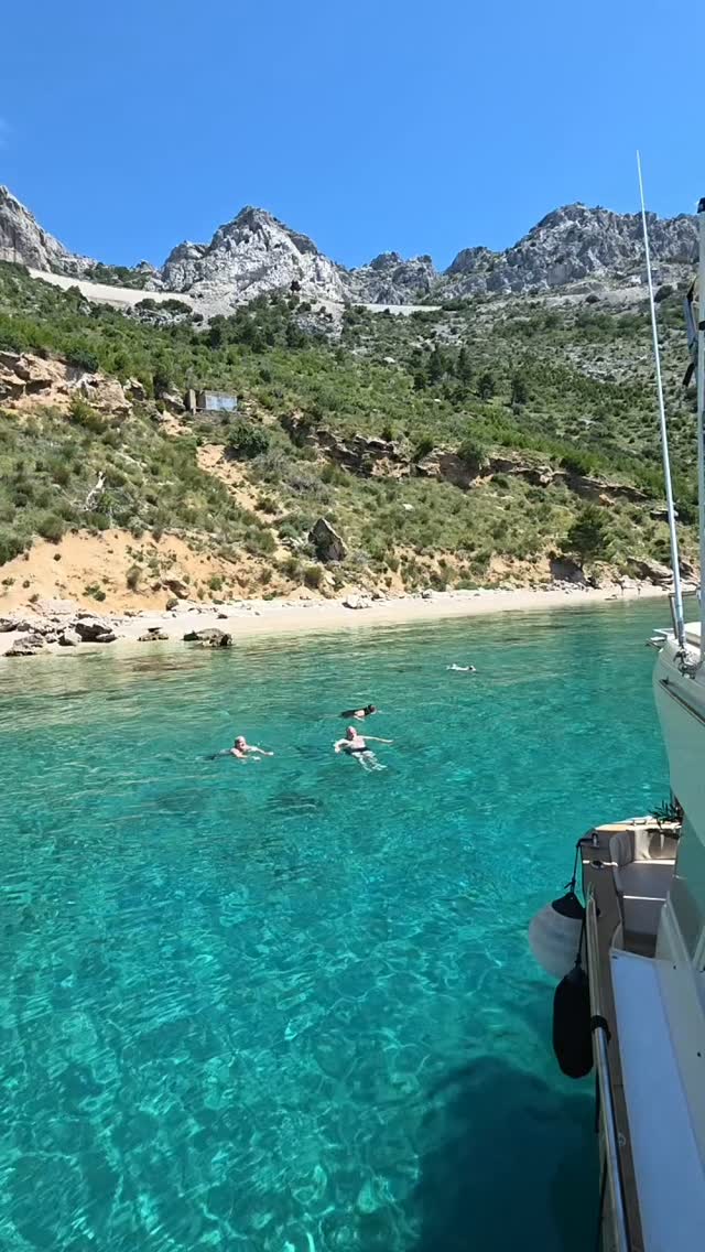 Guests swimming in a crystal-clear cove next to the boat